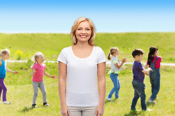 Image showing smiling woman over group of little kids outdoors