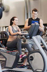 Image showing happy woman with trainer on exercise bike in gym