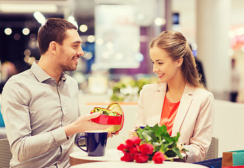 Image showing happy couple with present and flowers in mall