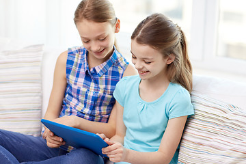 Image showing happy girls with tablet pc sitting on sofa at home