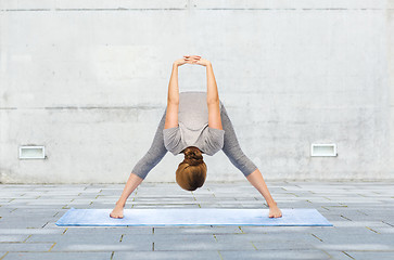 Image showing woman making yoga wide-legged forward bend on mat