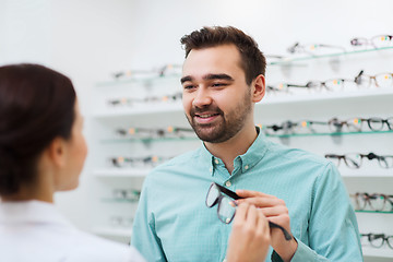 Image showing optician showing glasses to man at optics store