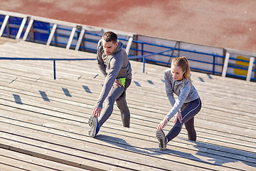 Image showing couple stretching leg on stands of stadium