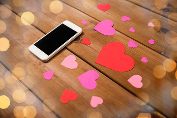 Image showing close up of smartphone and hearts on wood