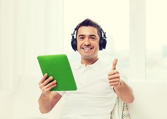 Image showing smiling man with tablet pc and headphones at home