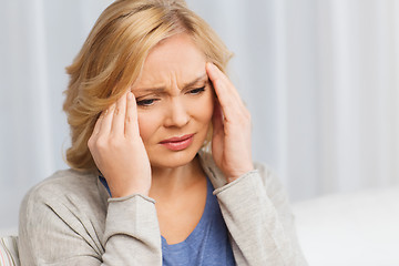 Image showing unhappy woman suffering from headache at home
