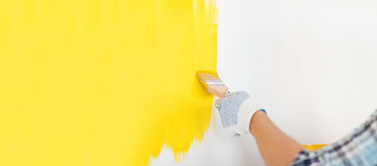 Image showing close up of male in gloves painting a wall