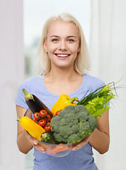 Image showing smiling young woman with vegetables at home