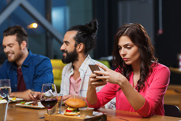 Image showing woman with smartphone and friends at restaurant