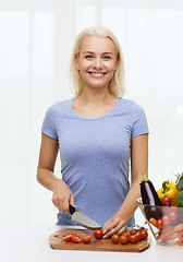 Image showing smiling young woman chopping vegetables at home