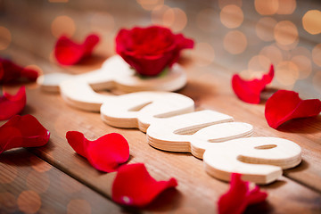 Image showing close up of word love cutout with red rose on wood