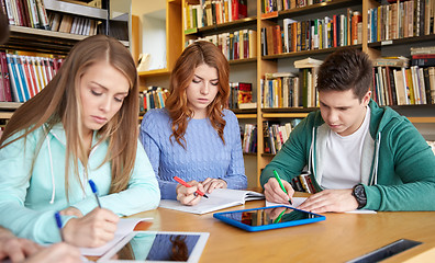 Image showing happy students writing to notebooks in library