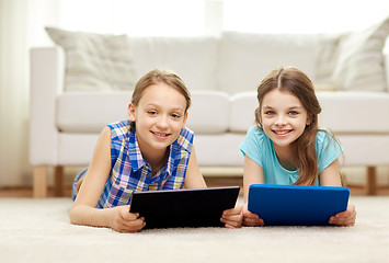 Image showing happy girls with tablet pc lying on floor at home