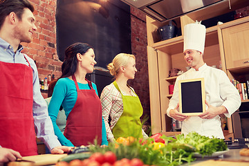 Image showing happy friends and chef cook with menu in kitchen