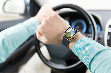 Image showing close up of male hands with smartwatch driving car