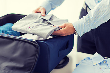 Image showing businessman packing clothes into travel bag