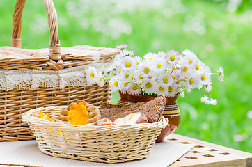 Image showing Buns in a wicker basket and a bouquet of flowers