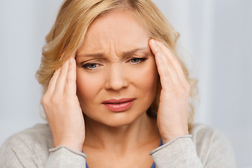 Image showing unhappy woman suffering from headache at home