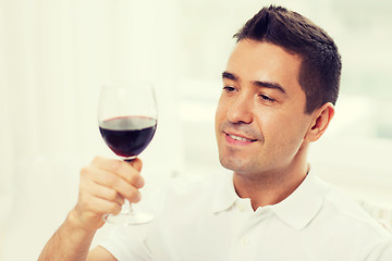 Image showing happy man drinking red wine from glass at home