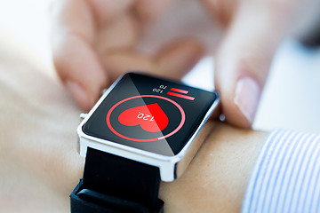 Image showing close up of hands with heart icon on smartwatch