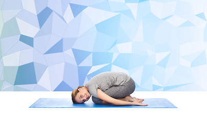 Image showing happy woman making yoga in child pose on mat