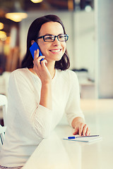 Image showing smiling woman calling on smartphone at cafe