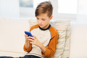 Image showing boy with smartphone texting or playing at home