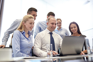 Image showing smiling business people with laptop in office