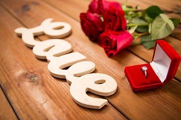 Image showing close up of diamond ring, red roses and word love