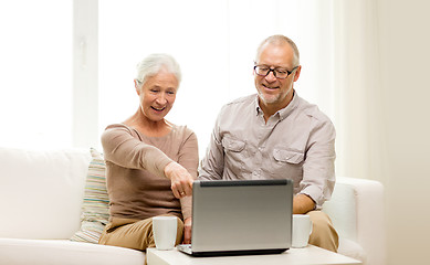 Image showing happy senior couple with laptop and cups at home