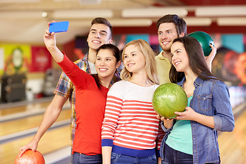 Image showing happy friends with smartphone in bowling club