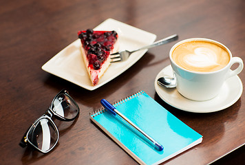 Image showing close up of notebook with pen, coffee cup and cake