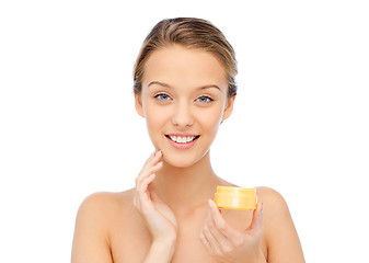 Image showing happy young woman applying cream to her face