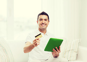 Image showing smiling man working with tablet pc at home