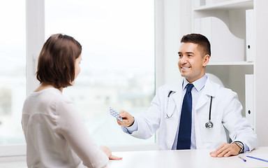 Image showing smiling doctor giving pills to woman at hospital