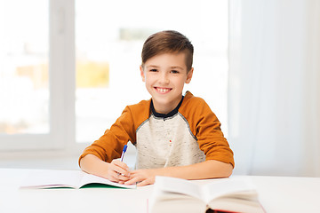 Image showing smiling student boy writing to notebook at home