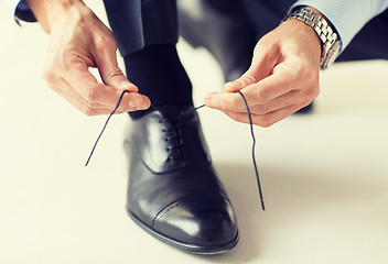 Image showing close up of man leg and hands tying shoe laces