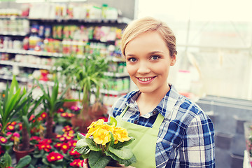 Image showing happy woman holding flowers in greenhouse