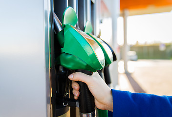 Image showing close up of hand holding hose at gas station