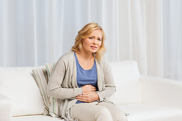 Image showing unhappy woman suffering from stomach ache at home