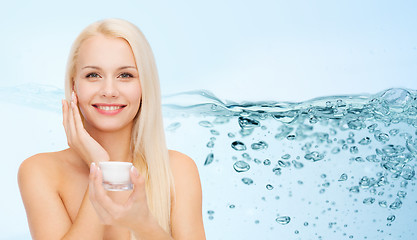 Image showing woman applying moisturizing cream to her face skin