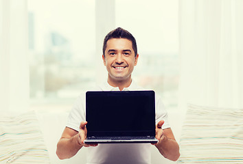 Image showing happy man showing laptop blank screen at home