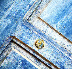 Image showing stripped paint in the blue wood door and rusty nail