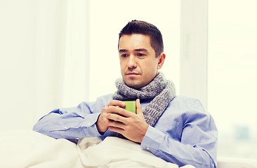 Image showing ill man with flu drinking hot tea from cup at home