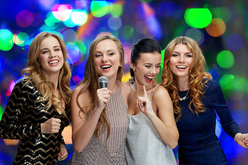 Image showing happy young women with microphone singing karaoke