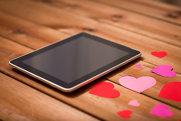 Image showing close up of tablet pc and hearts on wood