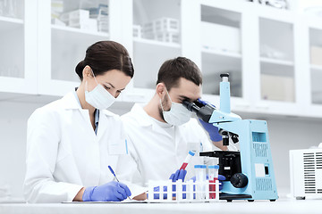 Image showing scientists with clipboard and microscope in lab