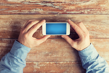 Image showing close up of male hands with smartphone on table