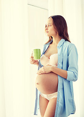 Image showing happy pregnant woman with cup drinking tea at home