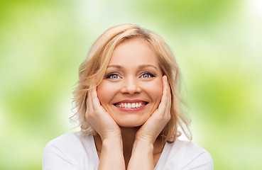 Image showing smiling woman in white t-shirt touching her face